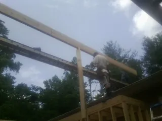 Carpenter setting a ridge beam over a new addition frame — Ice Dam Removal by Roofing Brothers in New Johnsonville