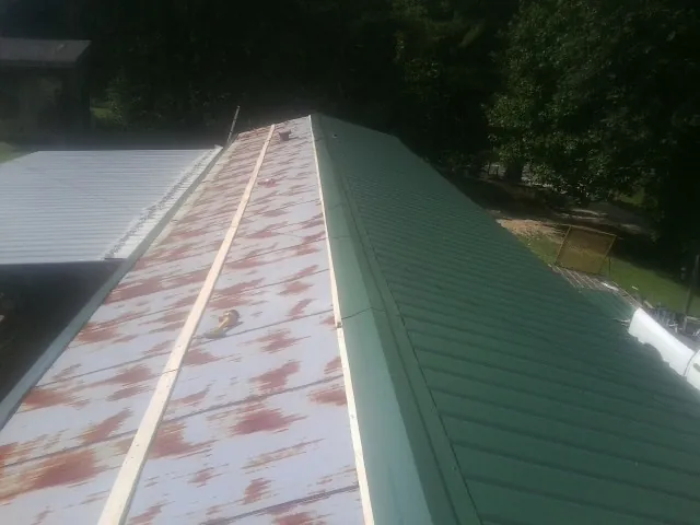 Old rusted panels beside newly installed green metal roofing — Wind Damage Roof Repair by Roofing Brothers in New Johnsonville