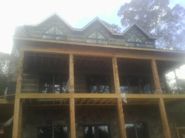 Dormers and porch framing on a large log home under construction — Roof Coating work by our crew in New Johnsonville