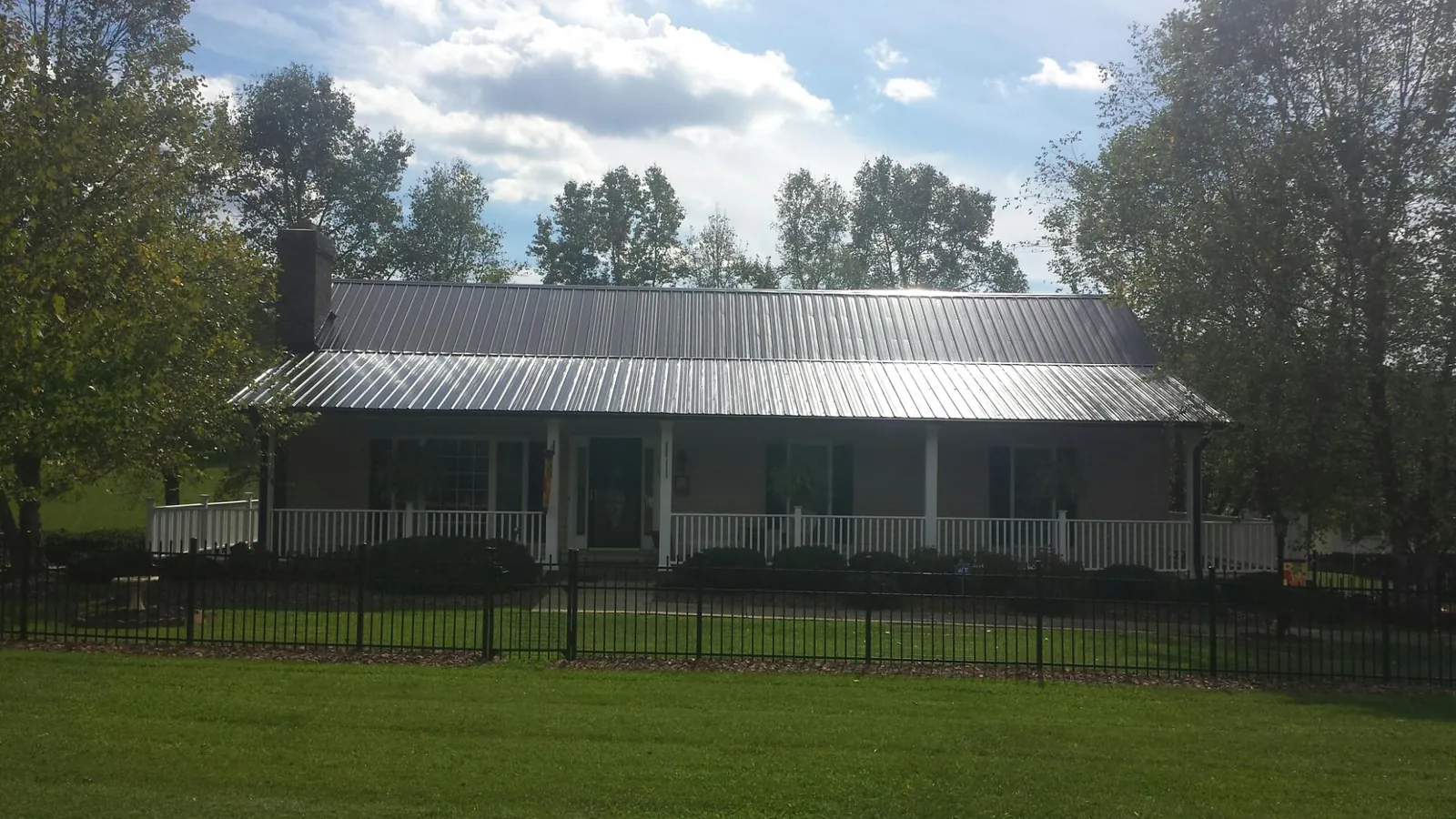 Gray metal roof on a brick ranch with a full width front porch — Gutter Guard Installation work by our crew in New Johnsonville