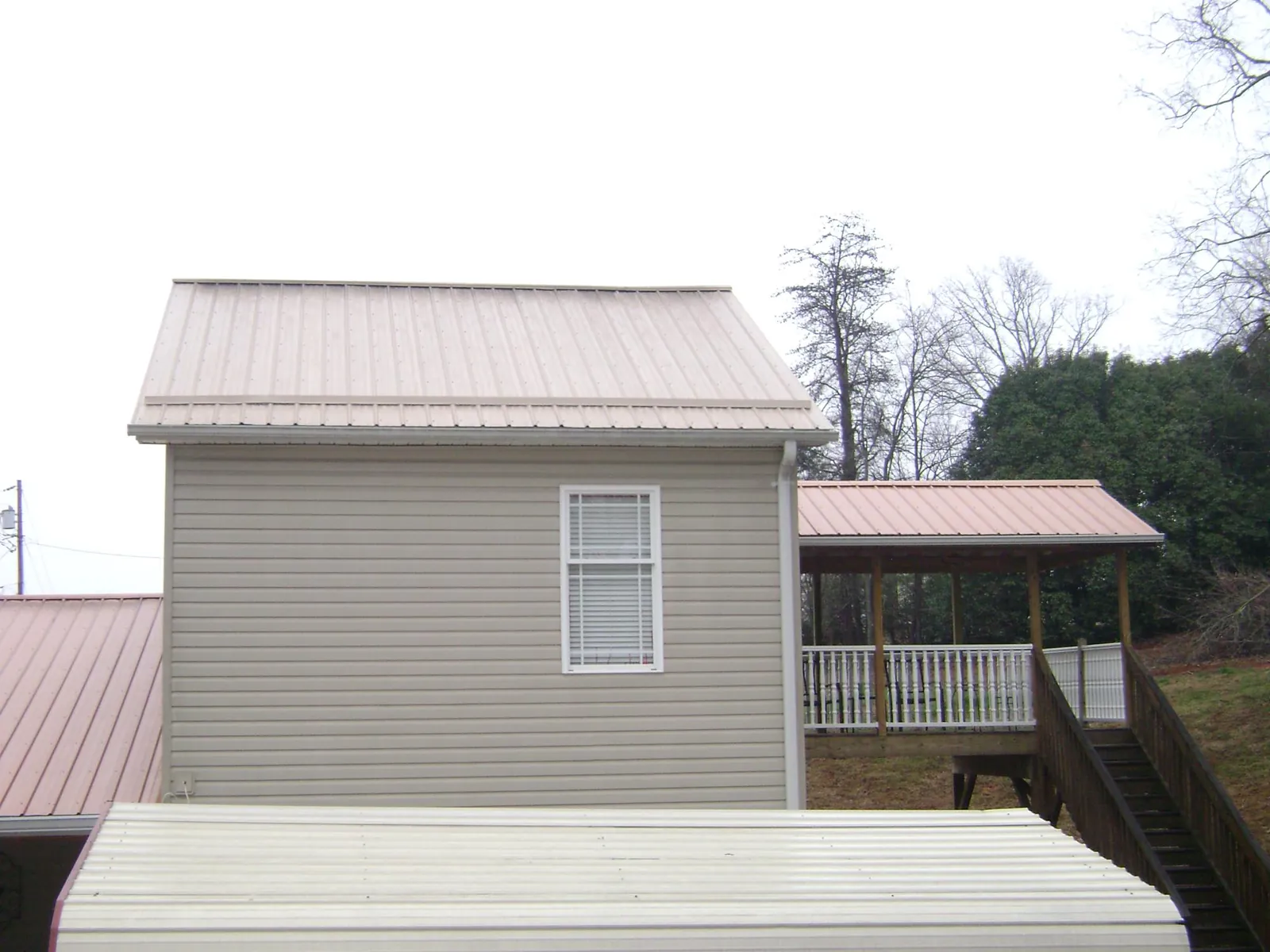 Tan metal roofs on a two story addition and attached porch, from a Roof Replacement job in New Johnsonville