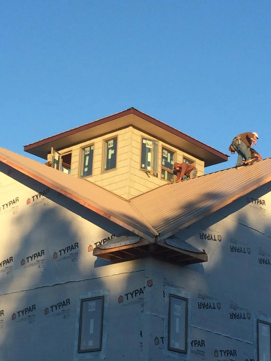Roofers working around a rooftop cupola on a new metal roof at sunset — Roof Waterproofing in New Johnsonville by Roofing Brothers
